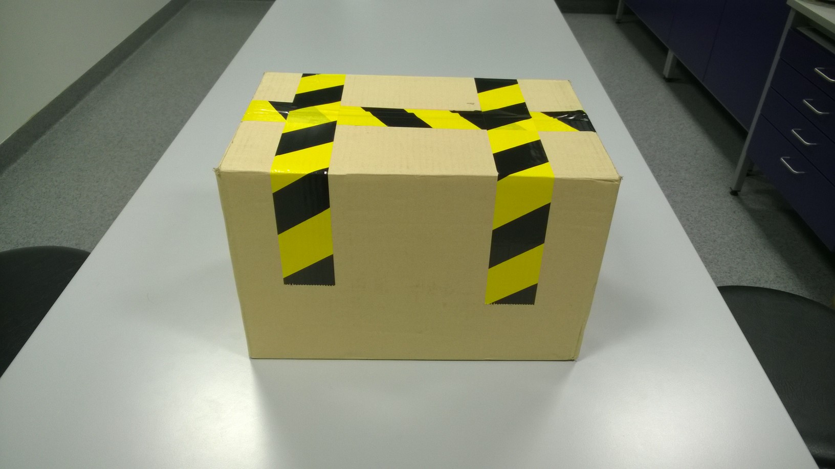 Tejpa igen f&ouml;rpackningen med bred tejp, anv&auml;nd gul-svartrandig tejp om s&aring;dan finns, f&ouml;rst&auml;rk vid behov botten p&aring; f&ouml;rpackningen