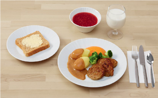 Kuvassa pehme&auml; ruoka-annos, jossa pehme&auml;ksi keitettyj&auml; perunoita ja parsakaalia, kastiketta, soseutettua porkkanaa ja pehmeit&auml; jauhelihapihvej&auml;. Lis&auml;ksi annos sis&auml;lt&auml;&auml; pehme&auml;&auml; leip&auml; levitteineen, ruokajuomana maitoa ja j&auml;lkiruokana marjakeittoa.